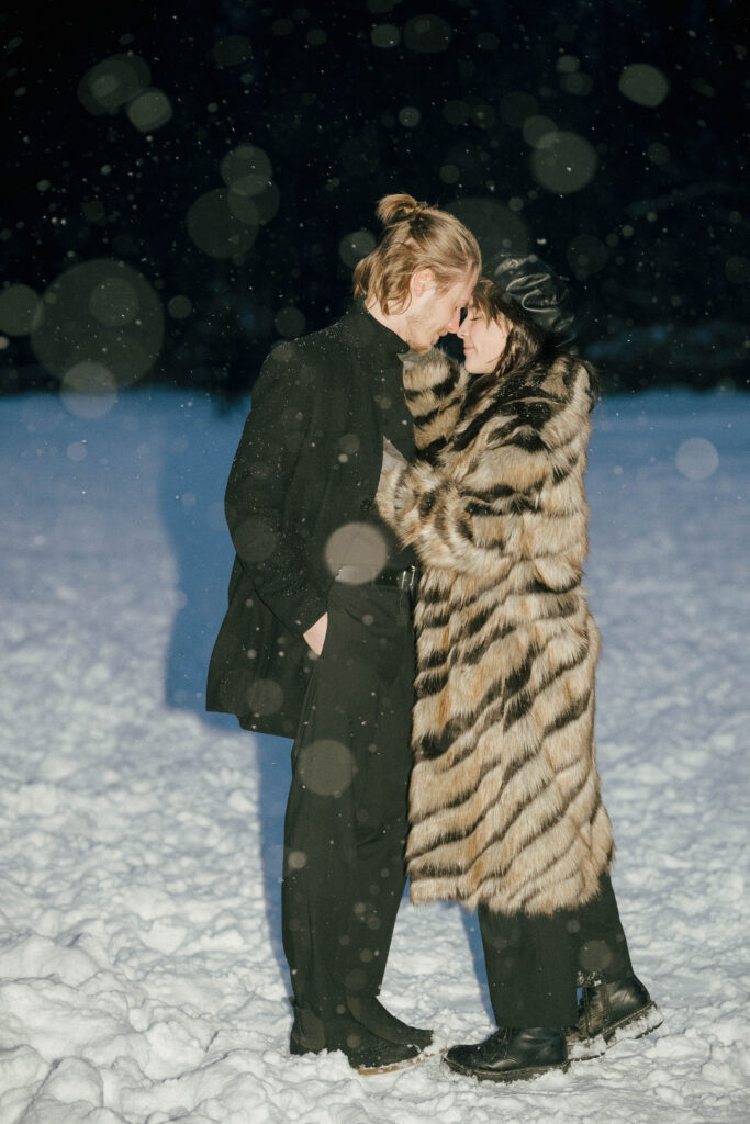 Couple in a fur coat standing in snow during a winter engagement session in Vancouver.