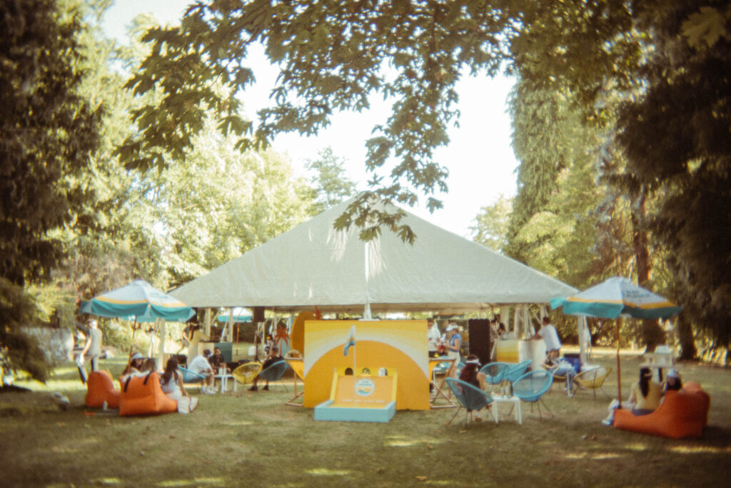 Outdoor event tent and colourful lounge seating across the Brock House lawn.
