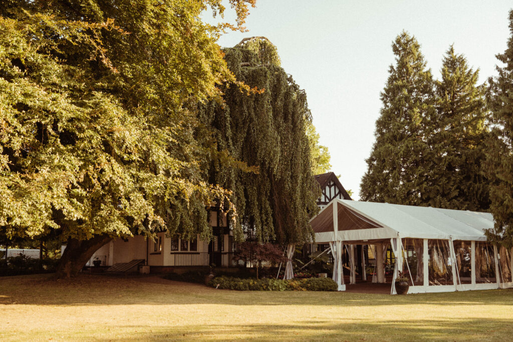 Brock House and its outdoor event tent surrounded by mature trees in Vancouver.
